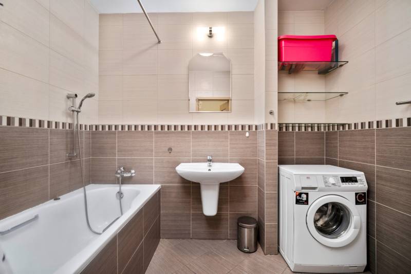 Badezimmer in einer 3-Zimmer-Wohnung mit Badewanne, Waschmaschine und Waschbecken.