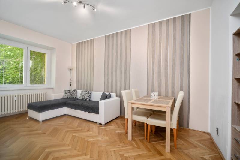Wohnzimmer mit Ecksofa, Tisch und Parkettboden in einer 3-Zimmer-Wohnung.