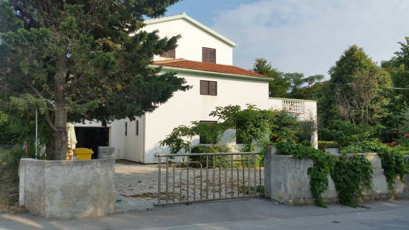 Ein Einfamilienhaus in Vrsi mit weißer Fassade, rotem Dach und umgebendem Grün.