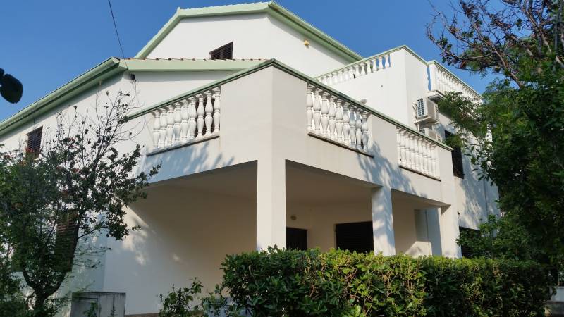 Ein Einfamilienhaus in Vrsi mit einem weißen Balkon und umgebendem Grün.