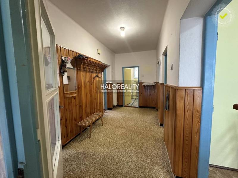 Küche in einem Einfamilienhaus mit Küchenzeile, Mikrowelle und Esstisch, erhellt durch ein großes Fenster.