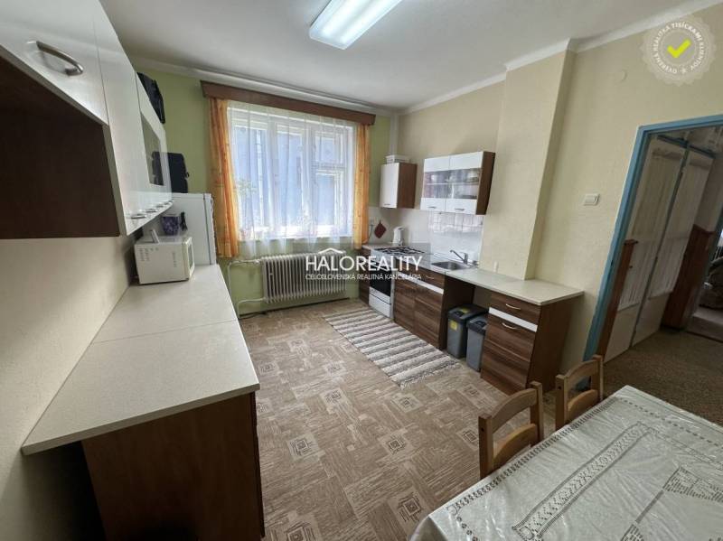 Küche in einem Einfamilienhaus mit Esstisch, Schränken und großem Fenster.
