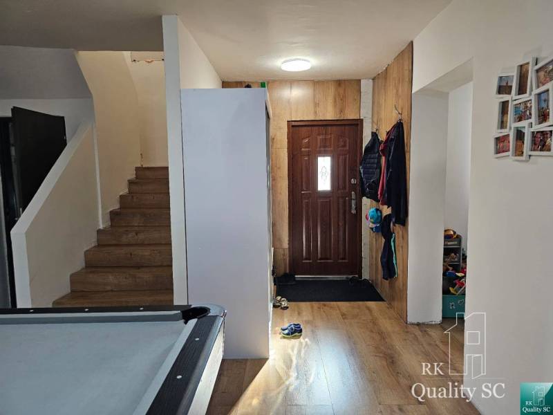 Eingangshalle in einem Einfamilienhaus mit Holztreppe und Stauraum.