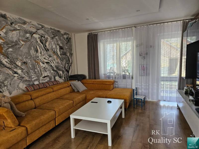 Obývačka in einem Einfamilienhaus mit einem großen Sofa, Kunst an der Wand und einem Tisch.