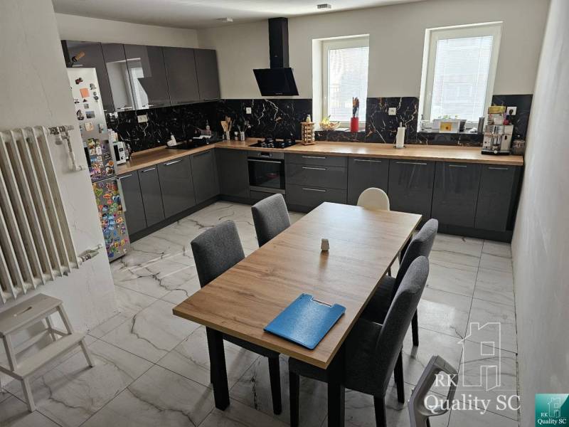 Eine Küche in einem Einfamilienhaus mit moderner Ausstattung und einem großen Tisch für sechs Personen.