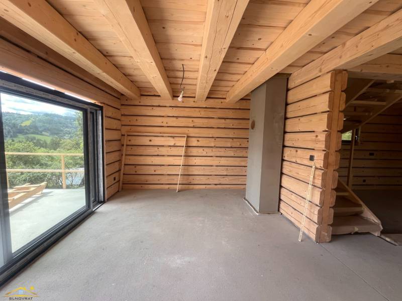 Interieur einer Holzhütte mit großem Fenster und Treppe.