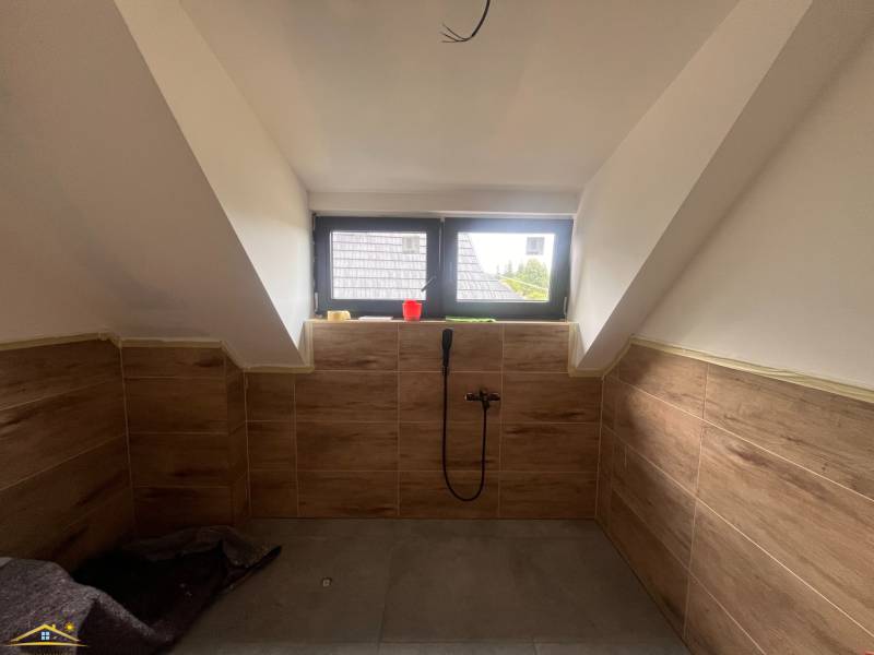 Ein Badezimmer im Dachgeschoss einer Hütte mit Holzverkleidung und Dachfenster.