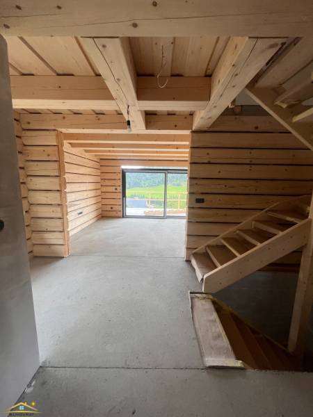 Eine Hütte mit einem hölzernen Interieur, einer Treppe und einem verglasten Ausblick auf die umliegende Natur.