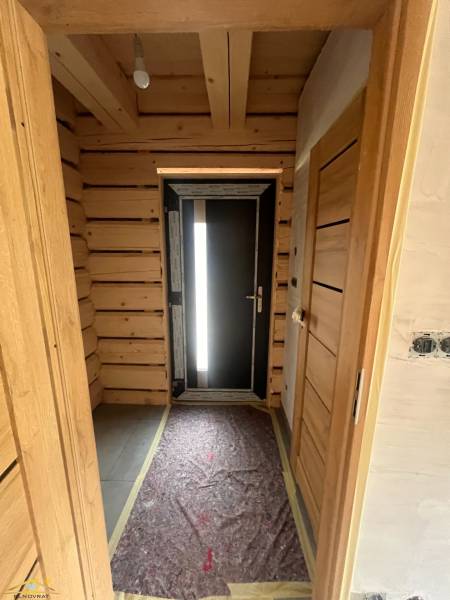 Holzflur in einer Hütte mit dunklen Türen und einer freiliegenden Glühbirne an der Decke.