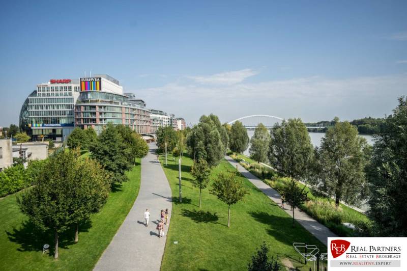Eurovea in Bratislava, Neue Stadt, Flussufer mit Gehweg und grünen Bäumen.