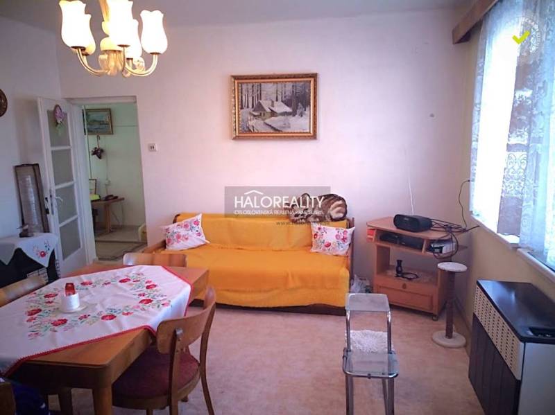 Wohnzimmer eines Einfamilienhauses mit Esstisch, Sofa und Radio auf dem Regal.