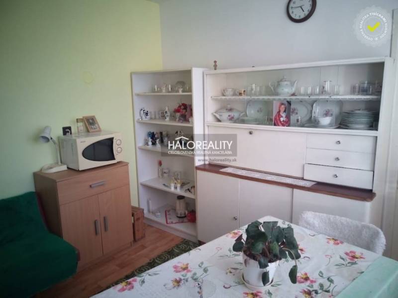 Innenraum eines Einfamilienhauses mit Retro-Möbeln, Mikrowelle und einem Esstisch mit geblümter Tischdecke.