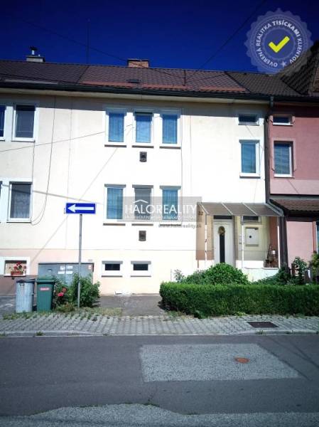 Ein Einfamilienhaus in Nováky mit weißer Fassade, grünen Sträuchern und einem Parkplatz vor dem Haus.