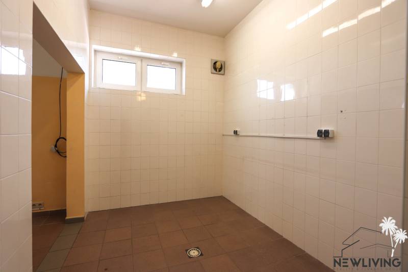 Ein gefliester Raum mit zwei Fenstern und einem Ventilator in Geschäftsräumen.