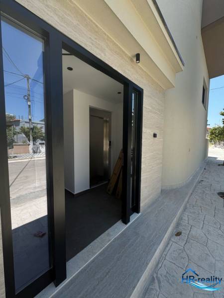 Der Eingang zum Ferienapartment in Ksamil hat Glastüren und ein helles Interieur.
