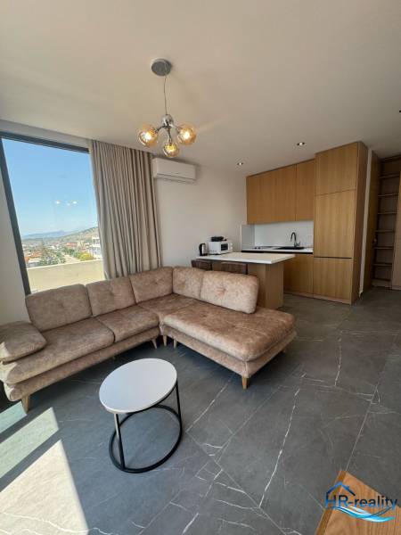 Wohnzimmer einer Ferienwohnung mit Ecksofa, Aussicht und Küchenzeile.