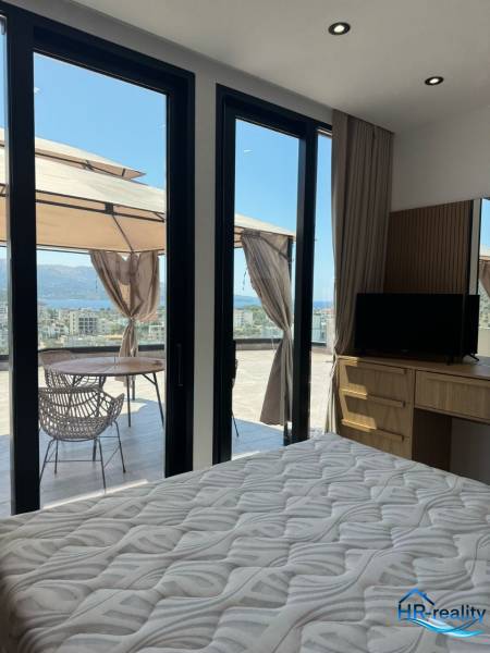 Innenraum einer Ferienwohnung mit Bett, Schrank und Terrasse mit Meerblick.