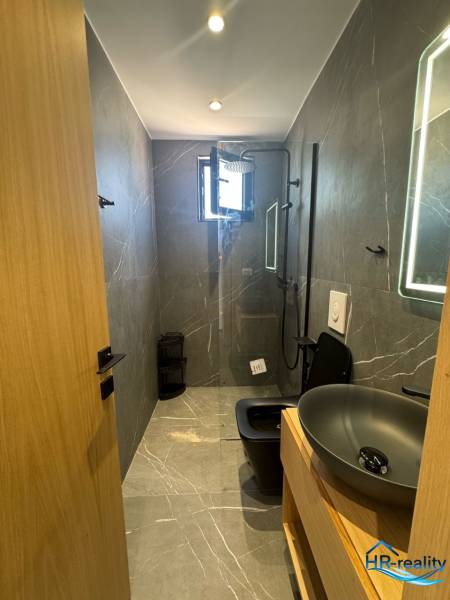 Ein Badezimmer in einem Ferienapartment mit Dusche, modernem Waschbecken und dunkler Toilette für Komfort.
