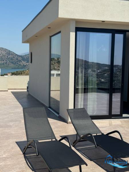 Terrasse einer Ferienwohnung in Ksamil mit Blick auf die Berge und zwei Liegestühlen.