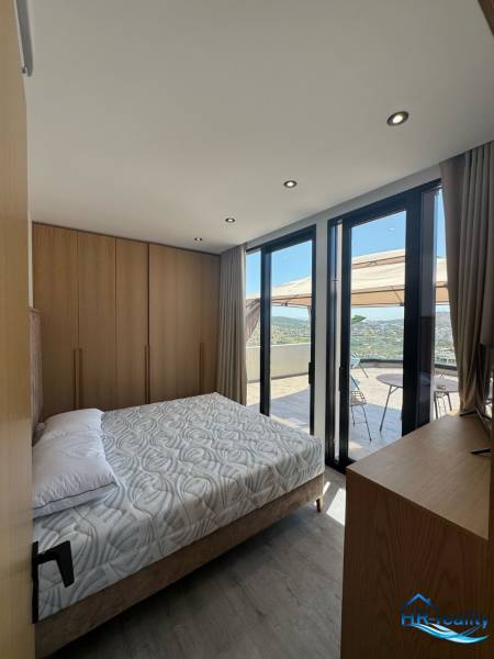 Schlafzimmer in einer Ferienwohnung mit Balkonblick, Holzmöbeln und Bett.