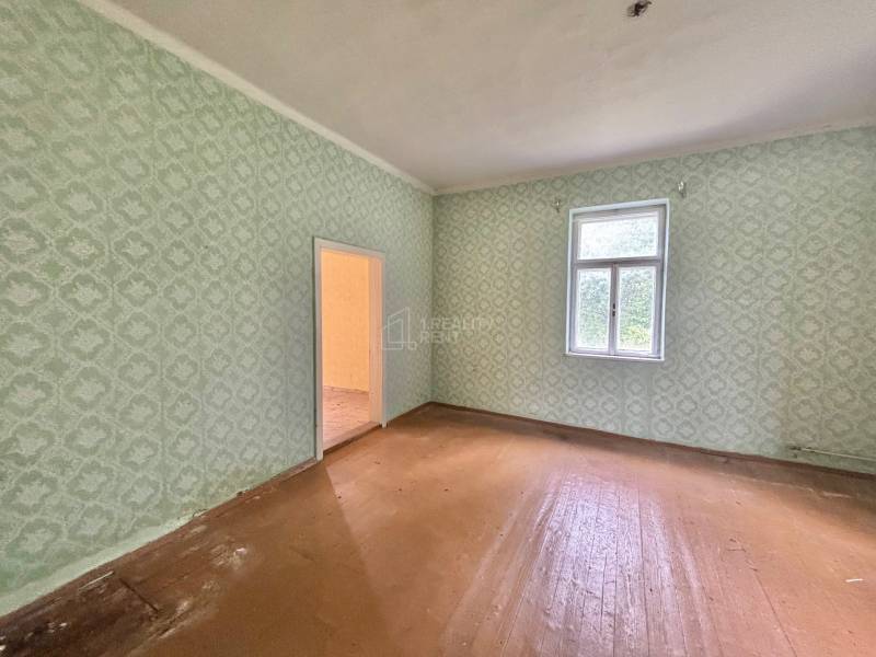 Geräumiges Zimmer in einem Einfamilienhaus mit Tapeten und Holzboden.