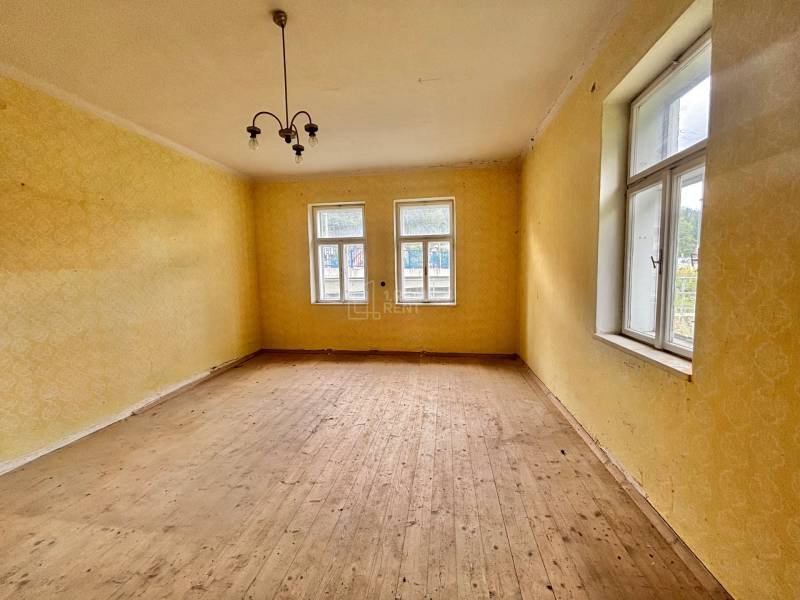 Ein Zimmer in einem Einfamilienhaus mit Holzboden, gelben Wänden und einer Hängelampe.
