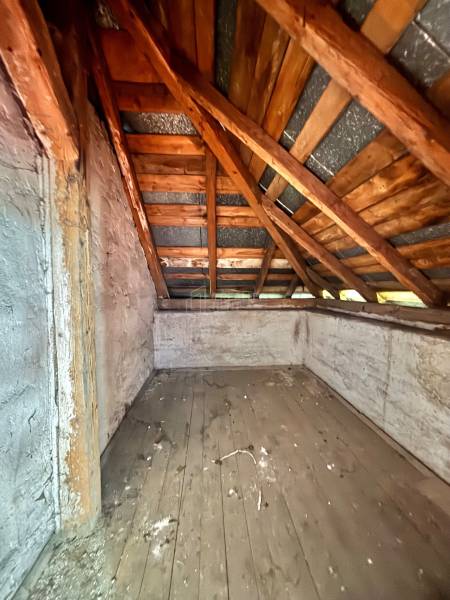 Dachboden eines Einfamilienhauses mit einem Holzdachstuhl und einem alten Holzbodenbelag.