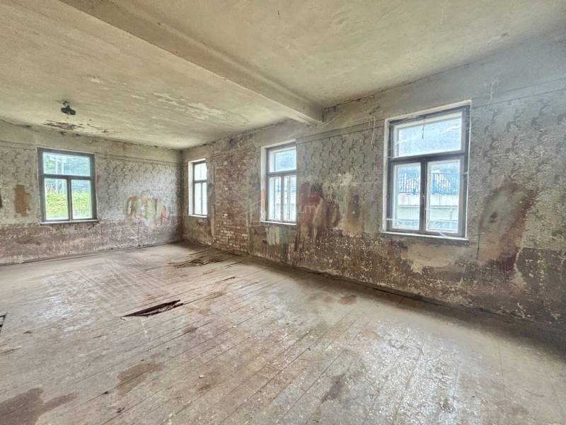 Ein verlassenes Zimmer in einem Einfamilienhaus mit beschädigten Böden und Wänden.