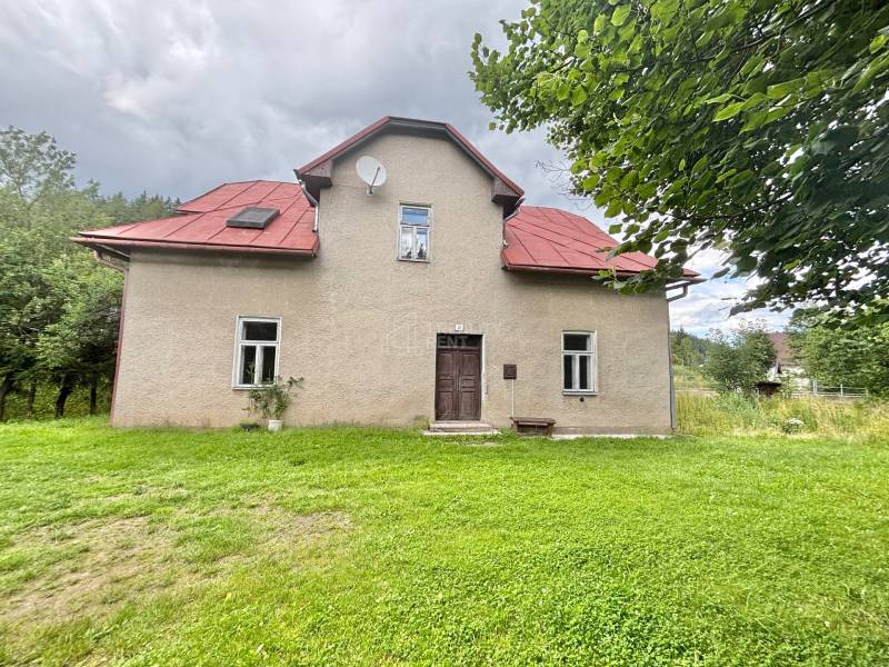 Einfamilienhaus im Zentrum, Makov, umgeben von einem grasbewachsenen Grundstück mit Bäumen.