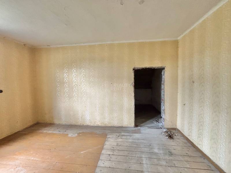 Ein Zimmer in einem Einfamilienhaus mit Holzboden und beigen Tapeten.