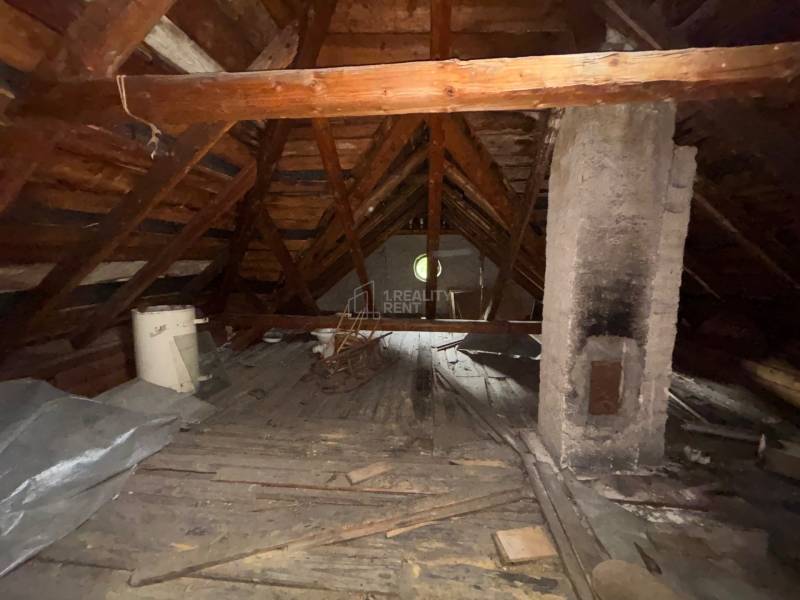 Das Dachgeschoss eines Einfamilienhauses mit Holzkonstruktion und einem gemauerten Schornstein.