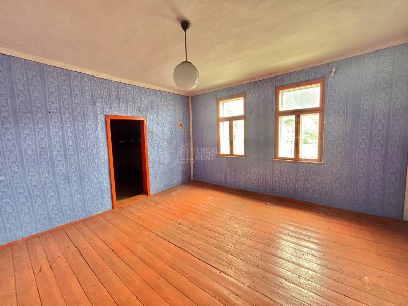Ein Zimmer in einem Einfamilienhaus mit Holzboden und blauer Tapete.