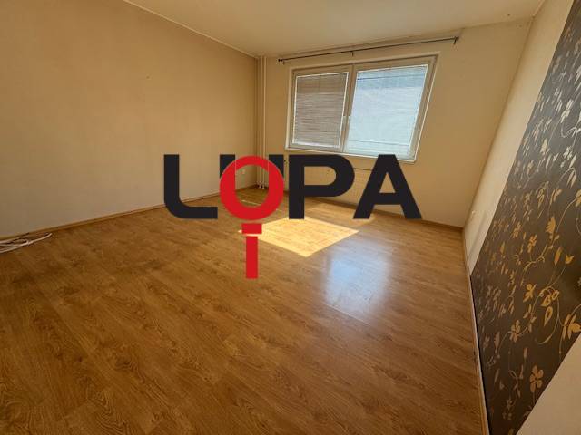 Ein Zimmer mit hellem Laminatboden und zwei Fenstern in einer 3-Zimmer-Wohnung.