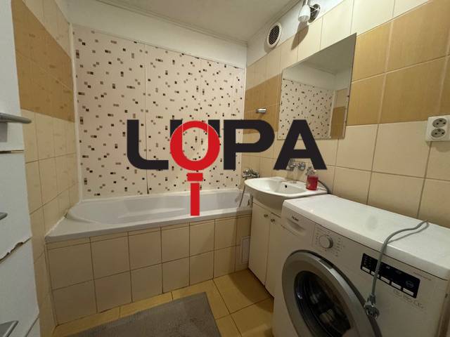 Badezimmer in einer 3-Zimmer-Wohnung mit Badewanne, Waschmaschine und Fliesen an den Wänden.