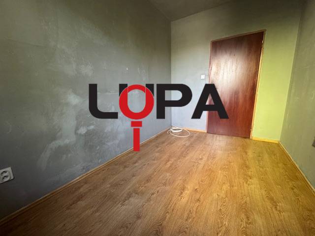 Ein Raum mit Holzboden und grauen Wänden in einer 3-Zimmer-Wohnung.