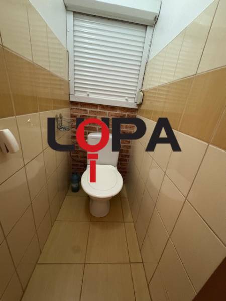 WC im 3-Zimmer-Wohnung mit braunen Fliesen und Fenster.