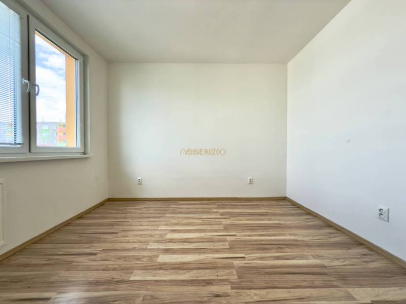 Ein leerer, heller Raum mit Holzboden in einer Vierzimmerwohnung.