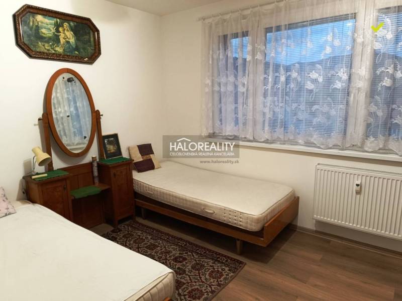 Zwei Betten, ein Spiegel, Bilder und ein Teppich im Zimmer einer Zweizimmerwohnung.