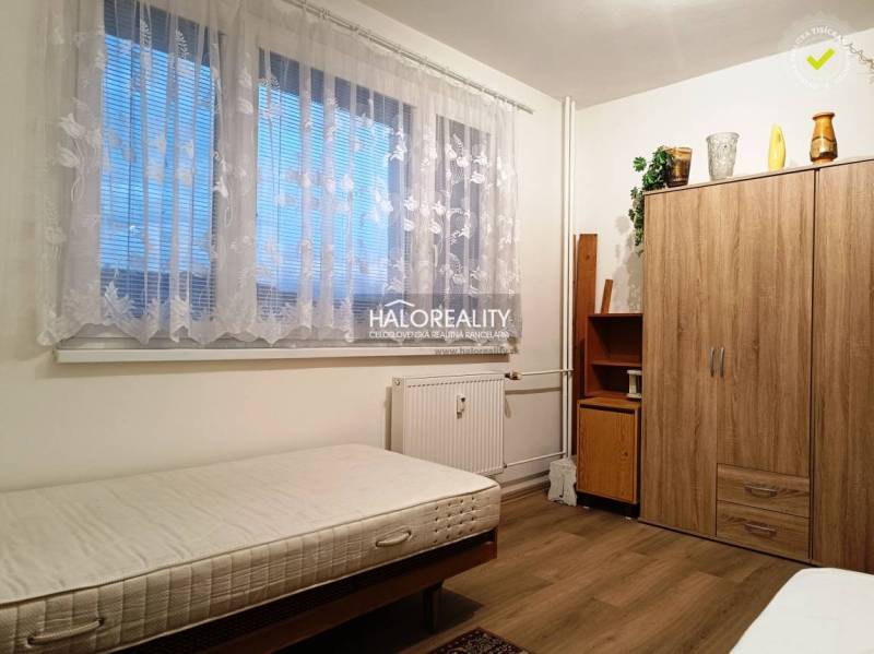Das Zimmer bietet ein einfaches Bett und einen Holzschrank in einer 2-Zimmer-Wohnung.