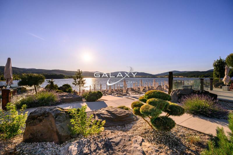 Der Garten am Wasser in Ružiná mit Blick auf den See und Liegestühlen bei Sonnenuntergang.
