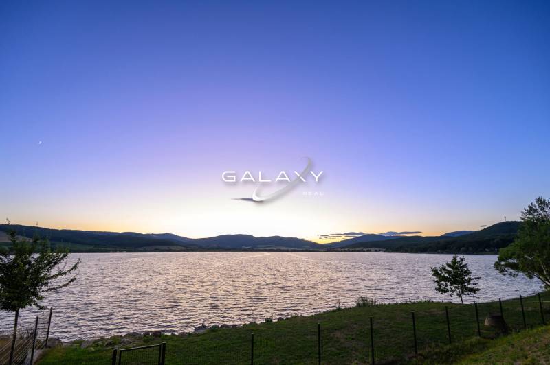 Ein See bei Sonnenuntergang, die ruhige Natur in der Umgebung von Ružiná und die Hütten.