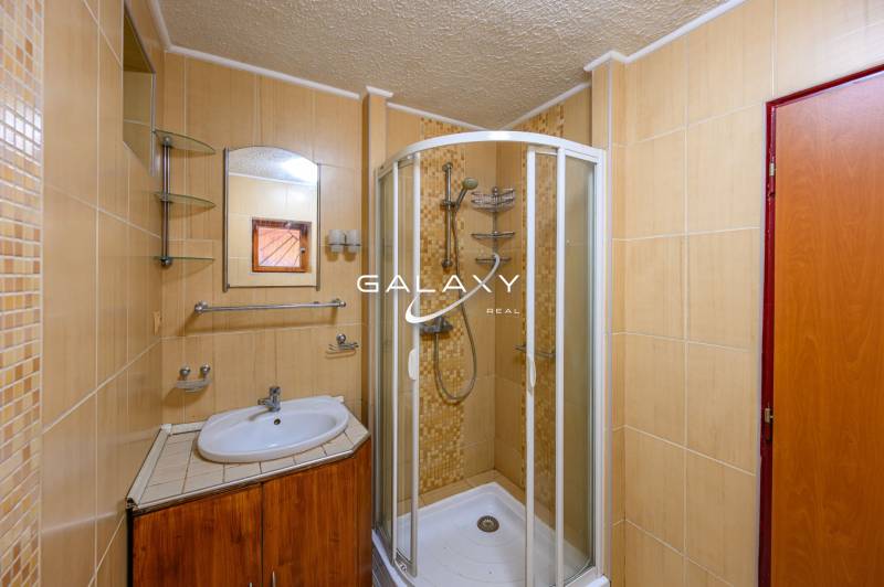 Ein Badezimmer in der Hütte mit einer Eckdusche, einem Waschbecken und einem Spiegel in gedämpften Tönen.