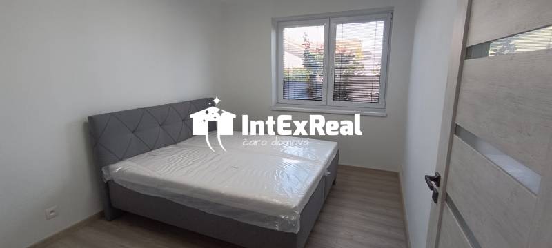 Schlafzimmer mit Bett und Fenster in einer 2-Zimmer-Wohnung, helle Wände und Boden.