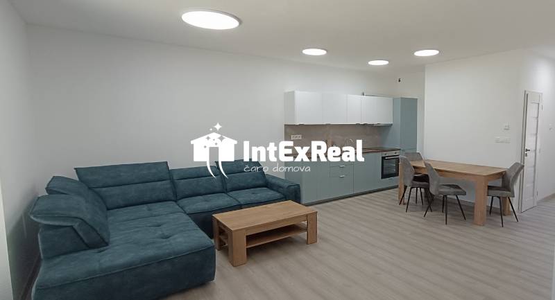 Das Wohnzimmer mit Küche umfasst ein bequemes Sofa, einen Holztisch und eine Küchenzeile.