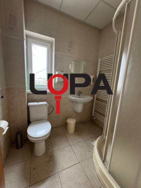 Badezimmer in Geschäftsräumen mit Sanitäranlagen, Dusche und Fenster für Tageslicht.