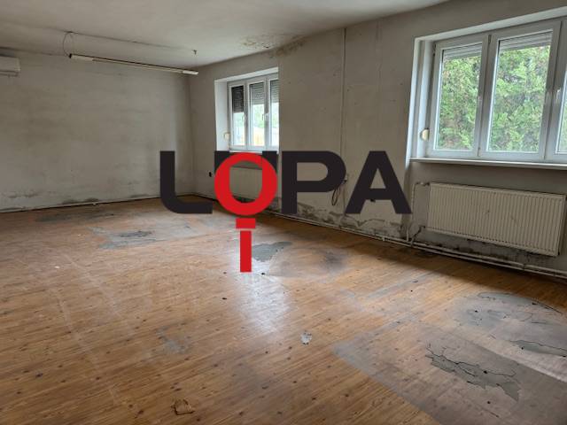Verlassener Raum in einem Gebäude mit Holzboden und großen Fenstern.