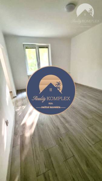 Helles Zimmer mit großem Fenster in einer 2-Zimmer-Wohnung und Holzboden.