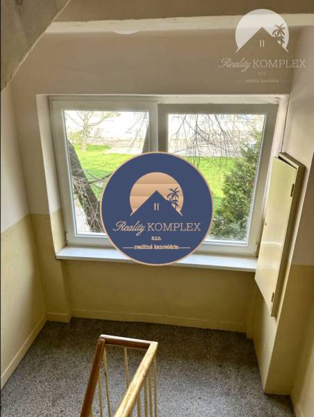 Flur mit Treppe und Fenster im Gebäude, draußen Grünfläche. Bietet eine 2-Zimmer-Wohnung an.