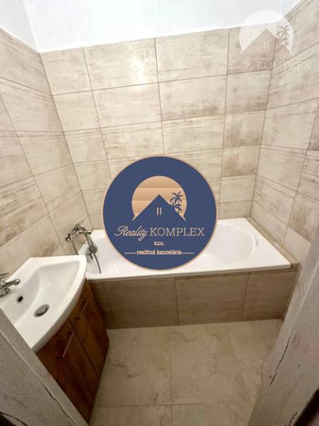 Badezimmer in einer 2-Zimmer-Wohnung mit Badewanne und Waschbecken, Fliesen in Beigetönen.