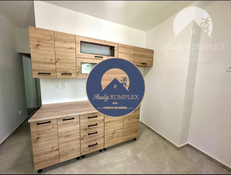 Küche in einer 2-Zimmer-Wohnung mit einem Holzschrank und Keramikboden.
